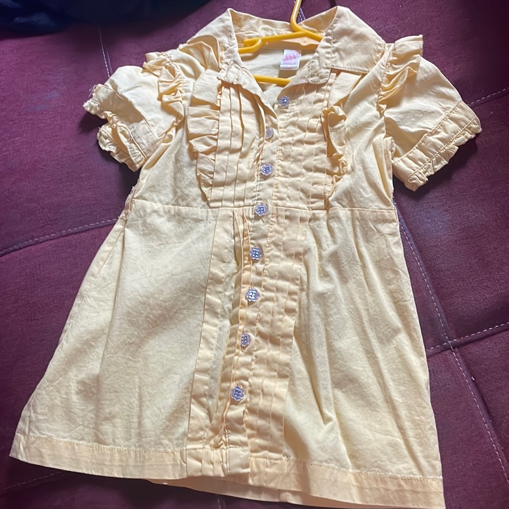This is a yellow casual shirt with clear flower buttons .
